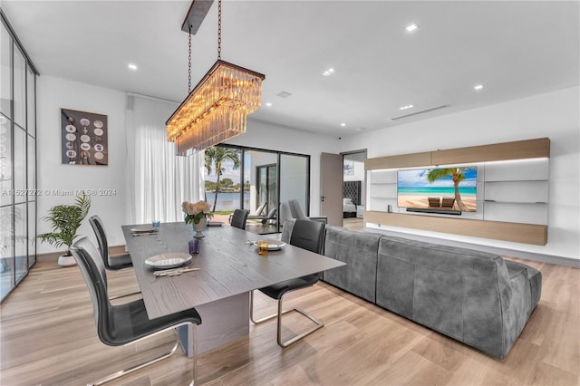 dining space with light hardwood / wood-style floors and a chandelier