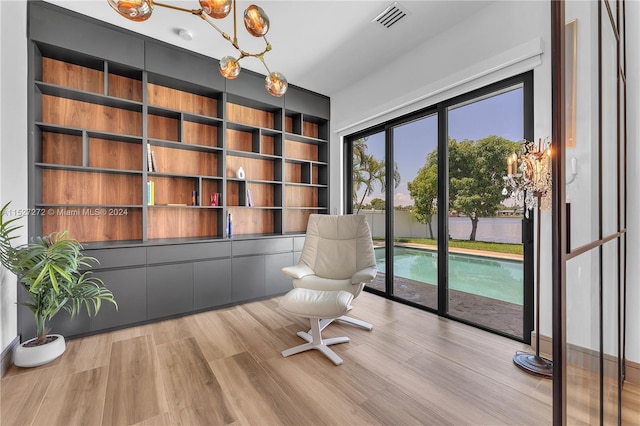 office area with a notable chandelier, light hardwood / wood-style floors, and built in shelves