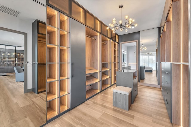 spacious closet featuring a notable chandelier and light hardwood / wood-style floors