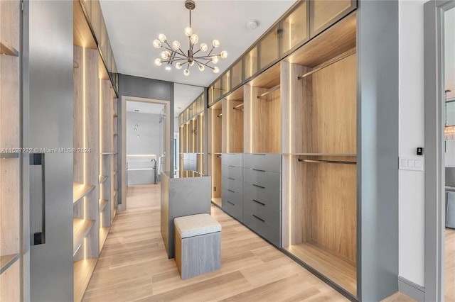 walk in closet featuring an inviting chandelier and light hardwood / wood-style flooring