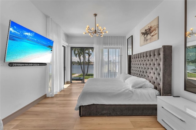 bedroom with a water view, multiple windows, a chandelier, and light hardwood / wood-style flooring