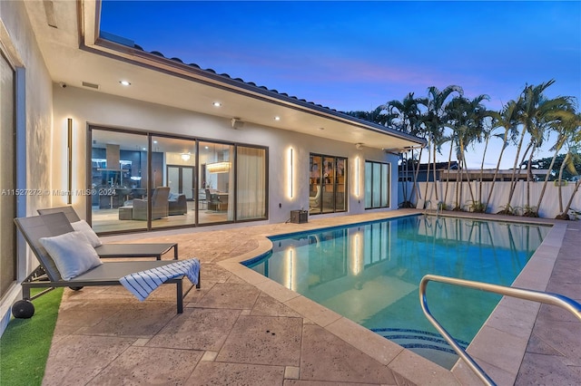 pool at dusk featuring a patio