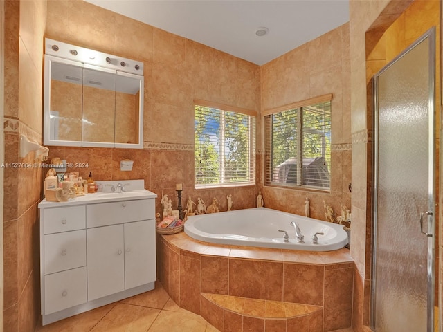 bathroom featuring tile walls, independent shower and bath, vanity with extensive cabinet space, and tile flooring