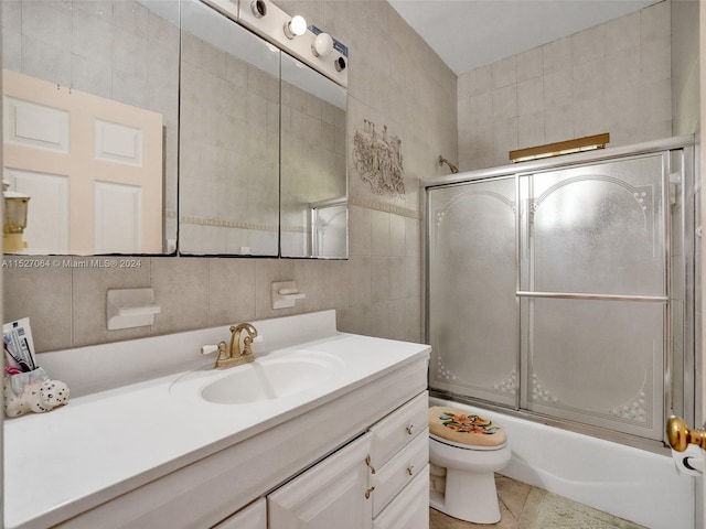 full bathroom featuring tile flooring, tile walls, enclosed tub / shower combo, toilet, and vanity with extensive cabinet space