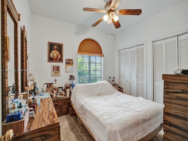 bedroom featuring light tile floors, ceiling fan, and two closets