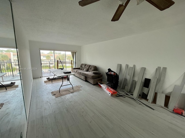 living room with light hardwood / wood-style floors, ceiling fan, and a textured ceiling