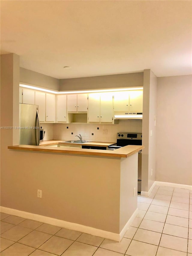 kitchen with white cabinetry, sink, light tile floors, tasteful backsplash, and stainless steel refrigerator