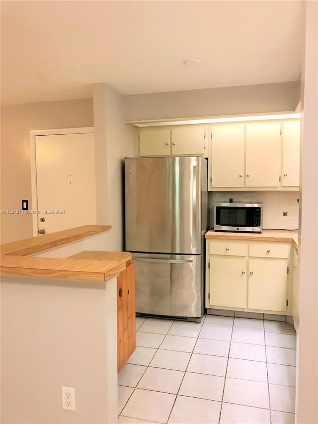 kitchen featuring appliances with stainless steel finishes, white cabinetry, and light tile flooring