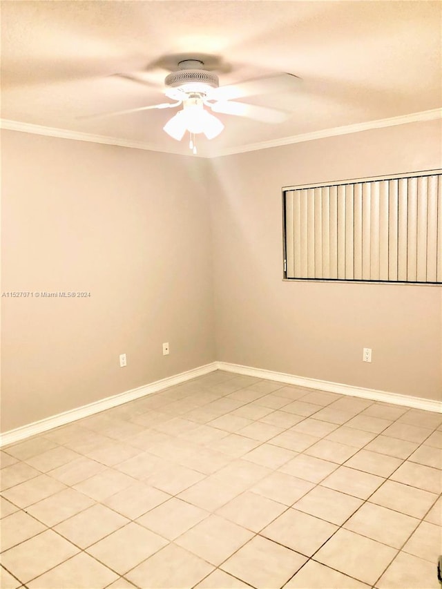 tiled empty room with ceiling fan and ornamental molding