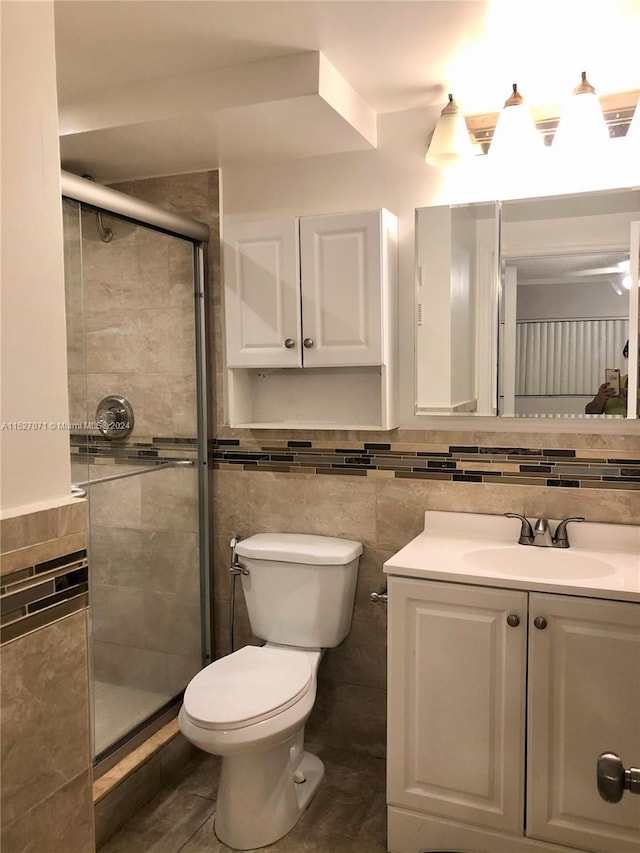 bathroom featuring vanity, tile walls, toilet, and walk in shower