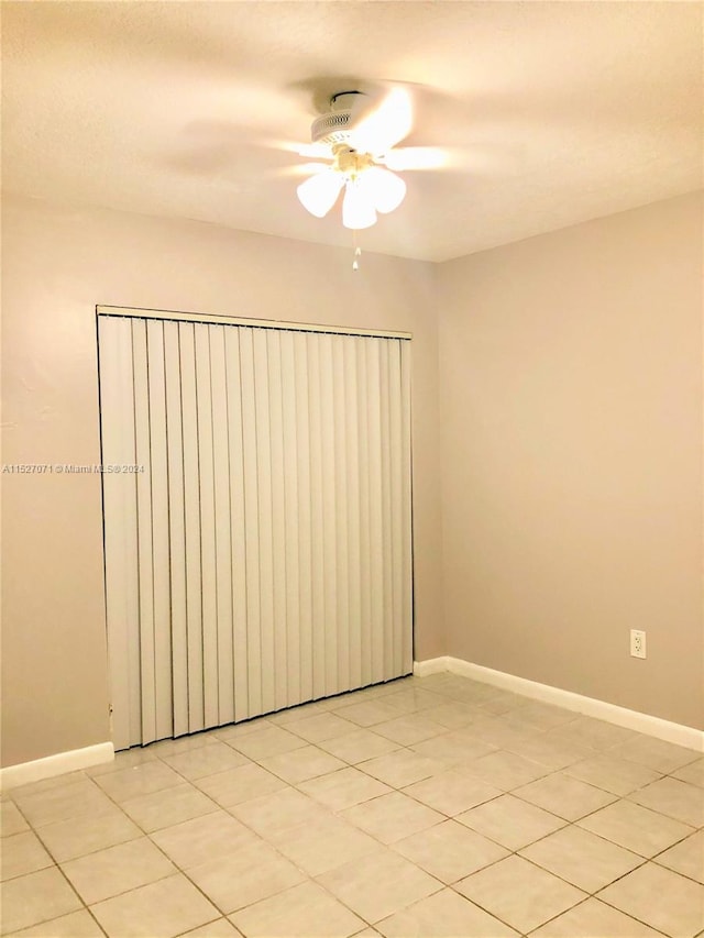 unfurnished room with ceiling fan and light tile floors