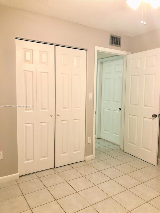 unfurnished bedroom featuring a closet and light tile floors