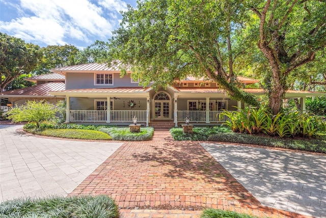 view of front facade featuring french doors, ceiling fan, and covered porch