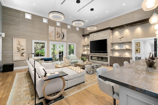 living room featuring french doors, ornamental molding, light hardwood / wood-style floors, and a high ceiling