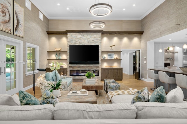 living room featuring a stone fireplace, ornamental molding, light hardwood / wood-style floors, and a towering ceiling