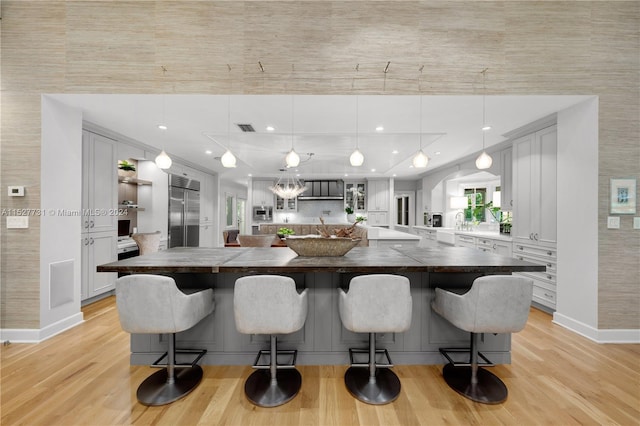 kitchen with built in appliances, pendant lighting, and a spacious island