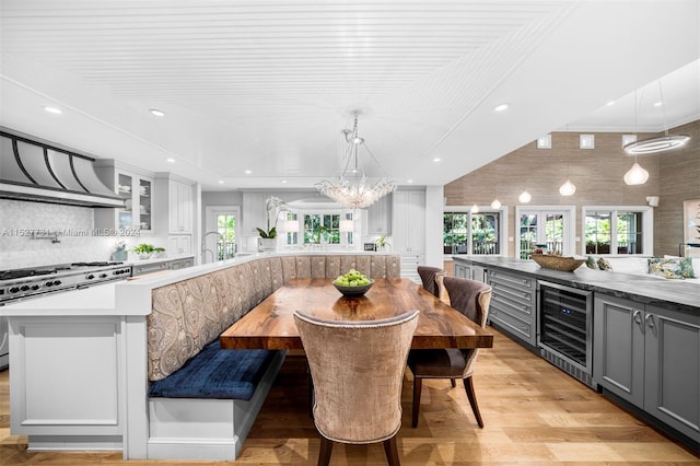 dining room with wine cooler, a chandelier, and light wood-type flooring