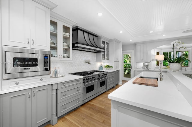 kitchen featuring gray cabinets, appliances with stainless steel finishes, sink, light hardwood / wood-style floors, and wall chimney range hood