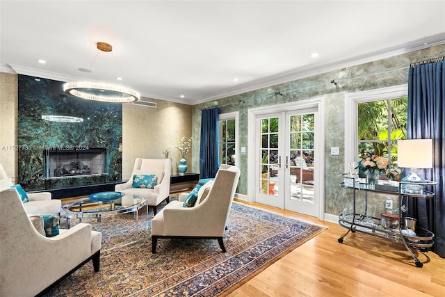 living room with a premium fireplace, crown molding, hardwood / wood-style floors, and french doors