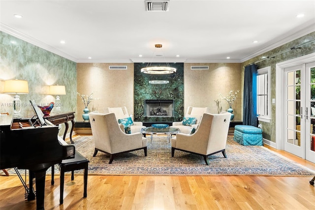 living area featuring hardwood / wood-style floors, a fireplace, ornamental molding, and french doors