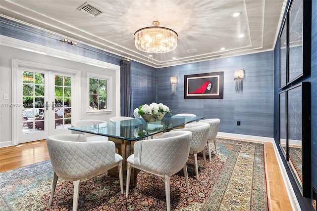 dining room with ornamental molding, hardwood / wood-style floors, a chandelier, and french doors