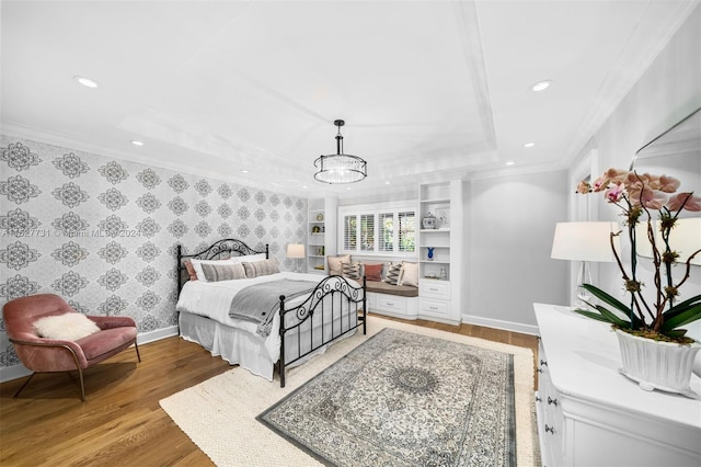 bedroom with a raised ceiling, crown molding, an inviting chandelier, and light hardwood / wood-style flooring