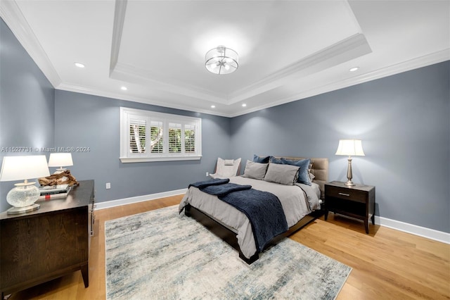 bedroom featuring a raised ceiling, ornamental molding, and hardwood / wood-style flooring