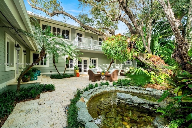 rear view of property with a patio area, french doors, and a balcony