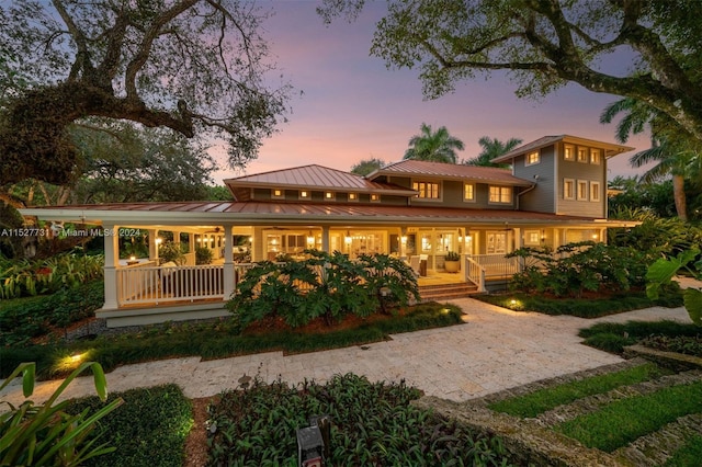 back house at dusk featuring a porch