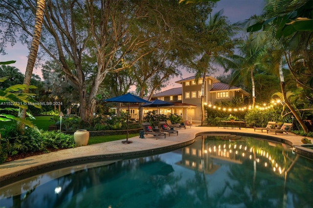 pool at dusk with a patio