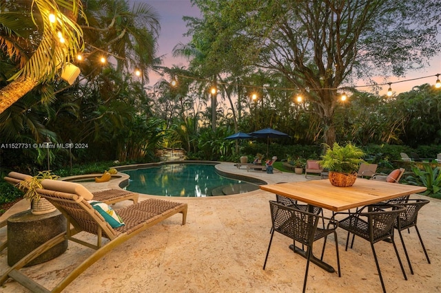 pool at dusk featuring a patio