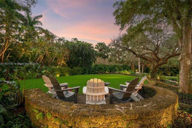 patio terrace at dusk featuring a lawn