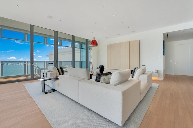 living room featuring a wall of windows, a water view, and light hardwood / wood-style floors