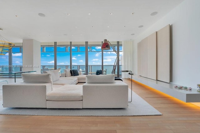 living room with a water view, a wall of windows, and light hardwood / wood-style floors