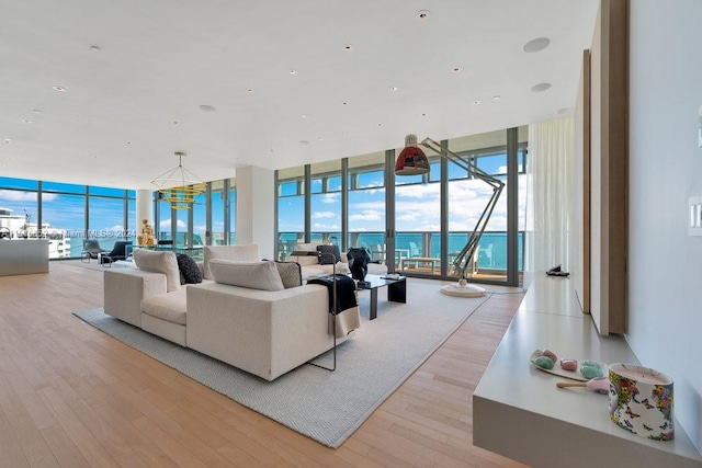 living room with a water view, a wall of windows, and light hardwood / wood-style floors