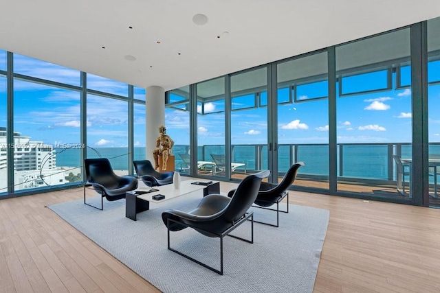 living room featuring light wood-type flooring, a water view, and floor to ceiling windows