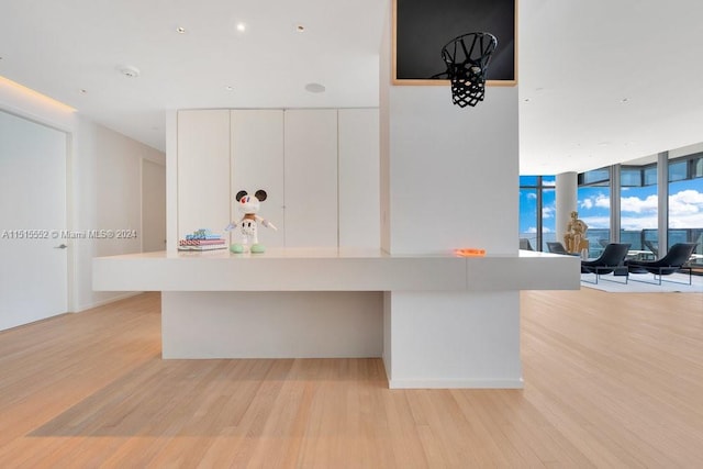 kitchen with light hardwood / wood-style flooring, floor to ceiling windows, and white cabinetry