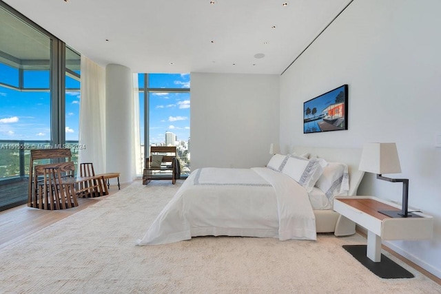 bedroom with floor to ceiling windows and light wood-type flooring