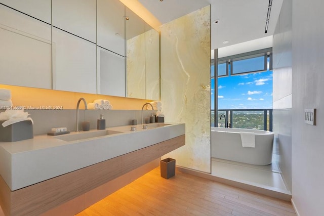 bathroom featuring rail lighting, hardwood / wood-style flooring, a bathing tub, and vanity