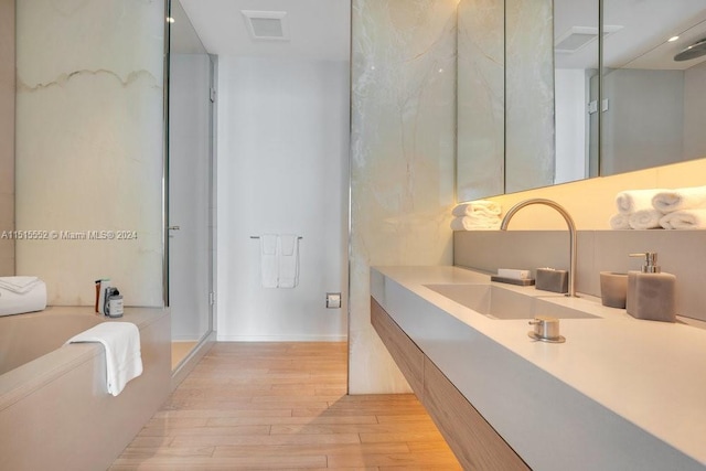 bathroom with separate shower and tub, hardwood / wood-style flooring, and vanity