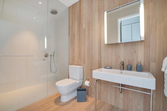 bathroom featuring vanity, toilet, wood-type flooring, and a tile shower