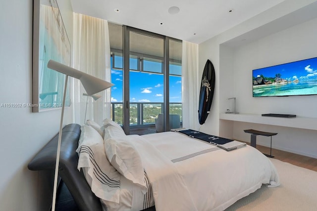 bedroom with a wall of windows and wood-type flooring