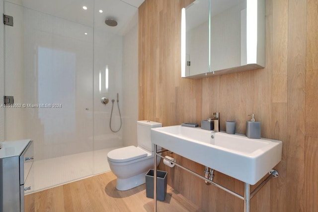 bathroom featuring toilet, wood-type flooring, walk in shower, and wooden walls