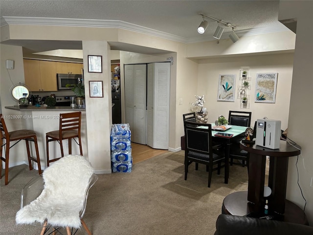 carpeted dining area with a textured ceiling, ornamental molding, and rail lighting