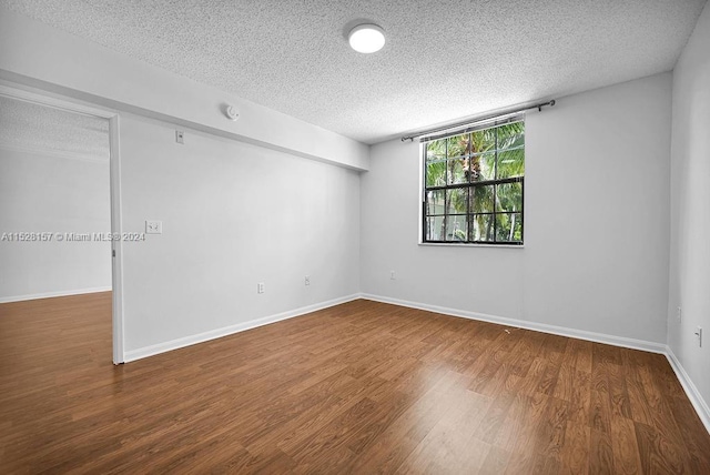 empty room with a textured ceiling and hardwood / wood-style flooring