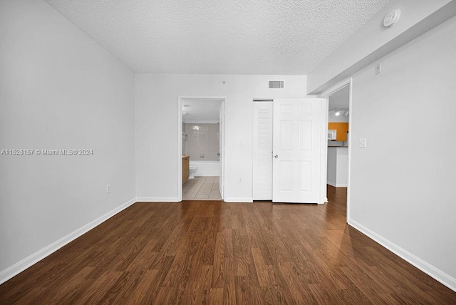 empty room with dark hardwood / wood-style flooring and a textured ceiling