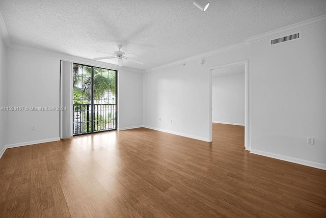 empty room featuring a textured ceiling, dark wood-type flooring, ceiling fan, and ornamental molding