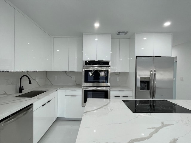 kitchen featuring light stone countertops, appliances with stainless steel finishes, and white cabinets