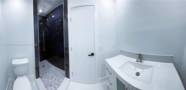 bathroom featuring a tile shower, tile patterned floors, vanity, and toilet