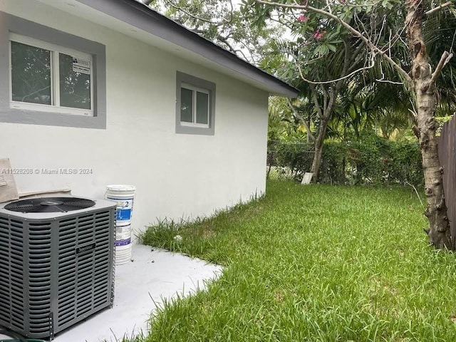 view of side of home with a lawn and cooling unit